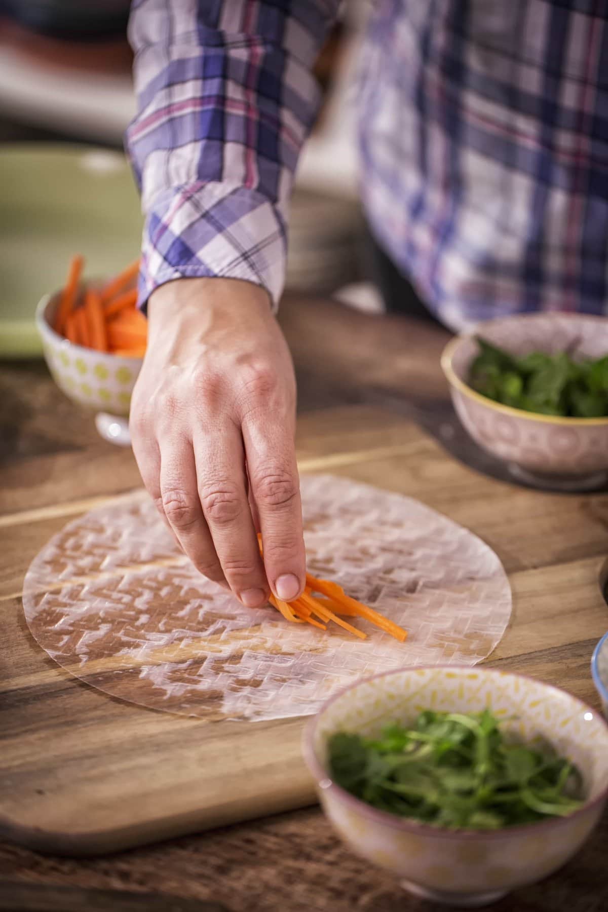 Picture of Man Rolling Vegan Spring Rolls on Wooden Cutting Board