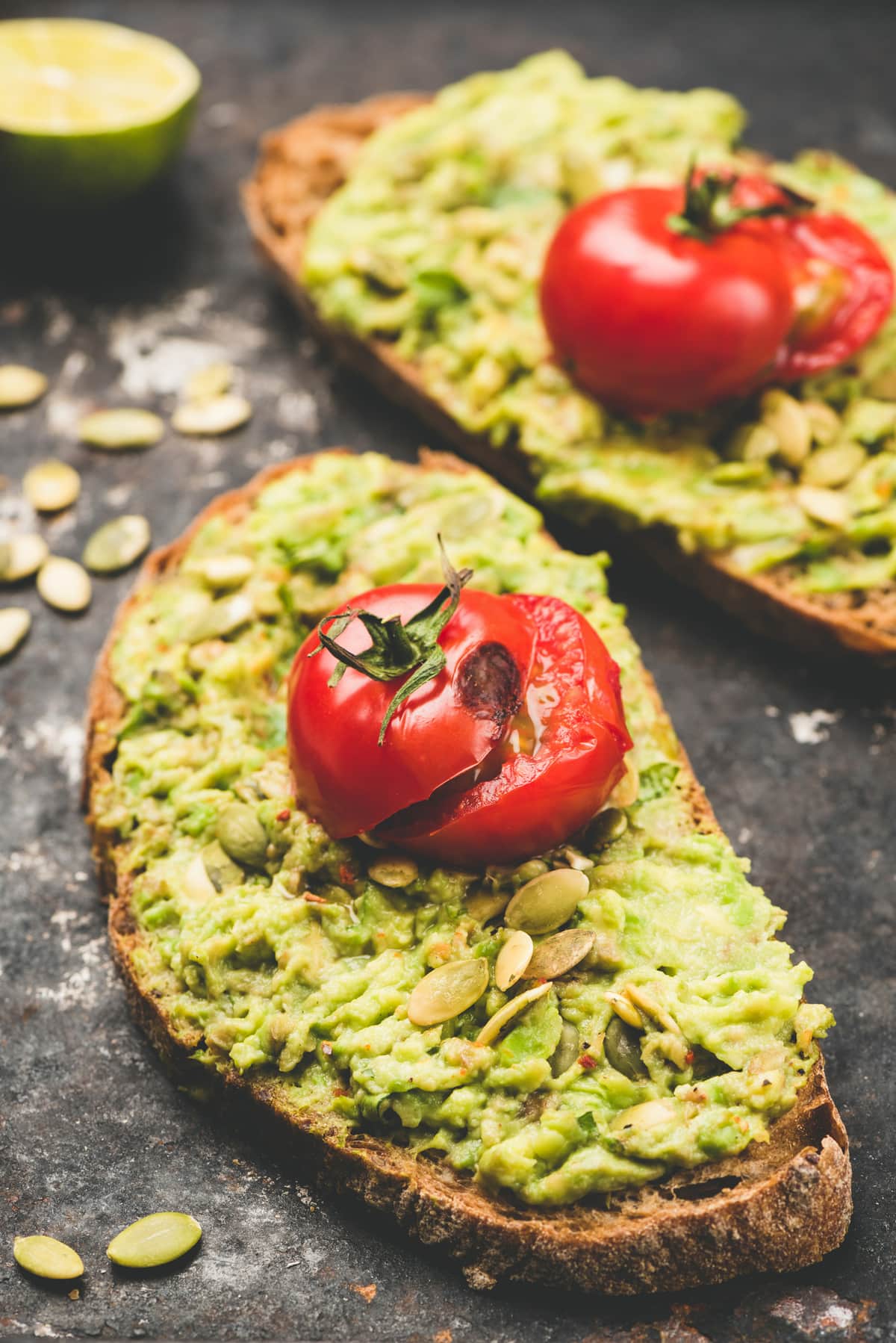 vegan avocado toast with roasted tomatoes and sunflower seeds on a table