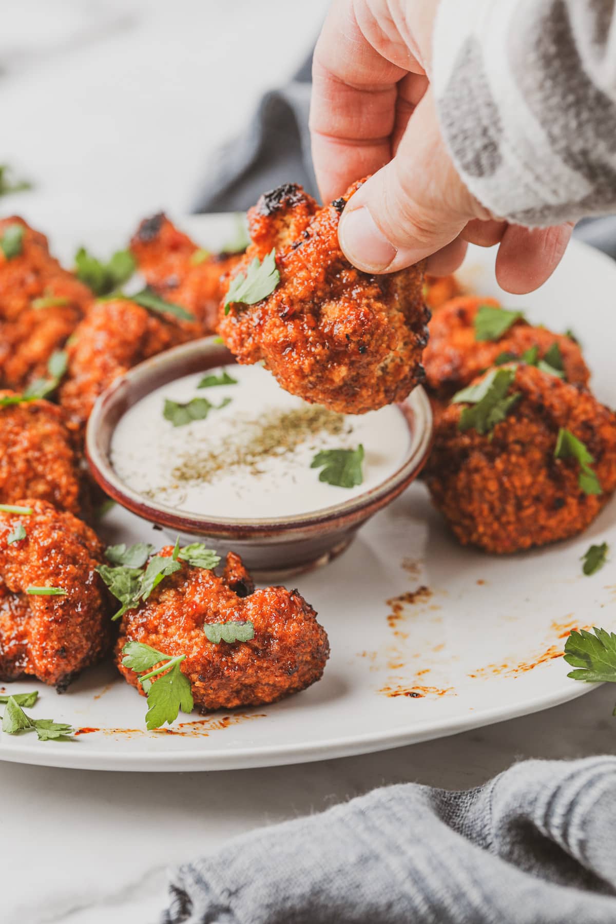 person dipping vegan cauliflower bites into dill ranch dressing