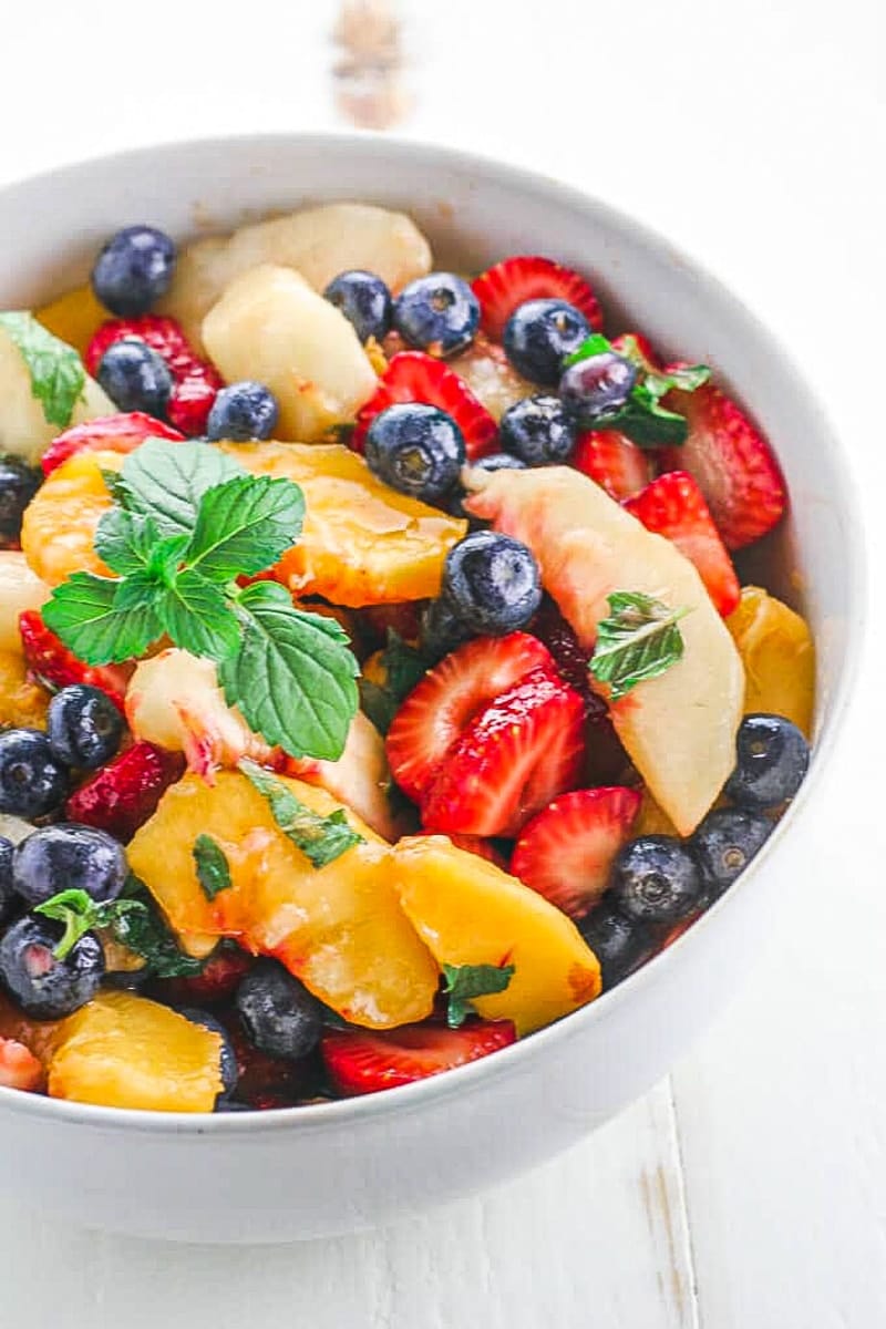 a vibrant fruit salad in a white bowl