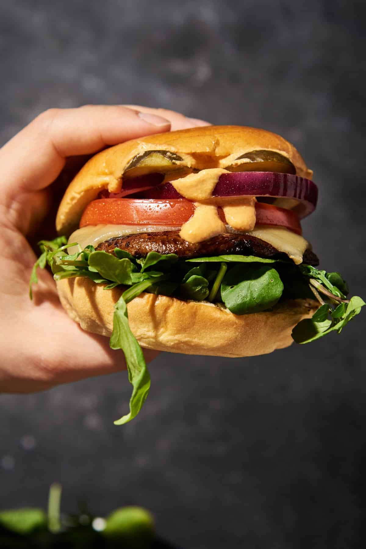 someone holding a Portobello mushroom burger in their hand