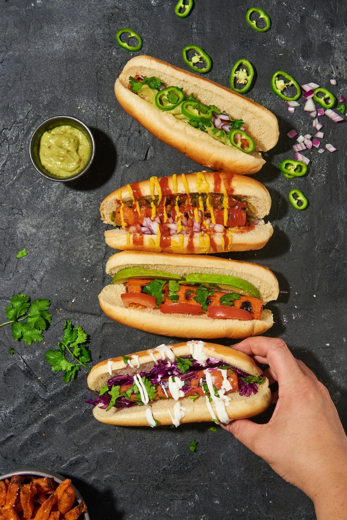 overhead shot of carrot hot dogs in buns on a dark table