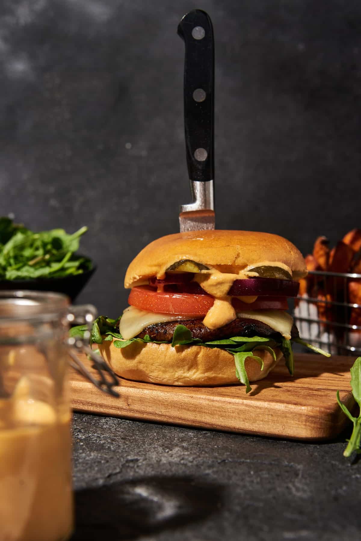 Portobello mushroom burger with all the toppings on a dark table