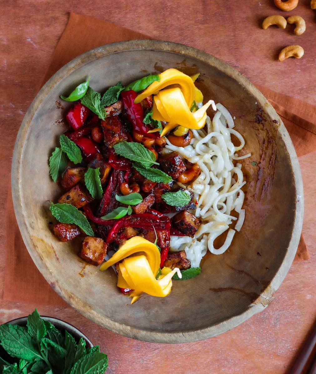 Thai basil tofu in a wooden bowl topped with basil and mint