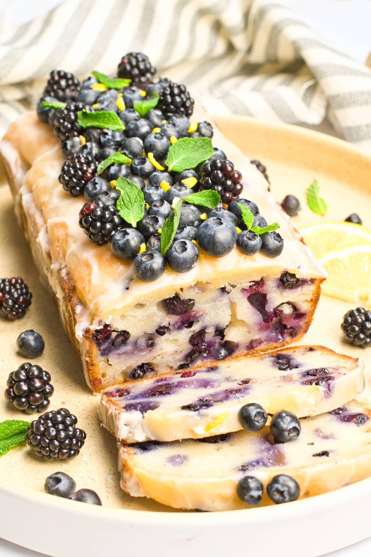 a loaf of blueberry bread topped with berries on a white plate