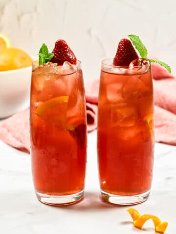 2 glasses of red beverage on a white table