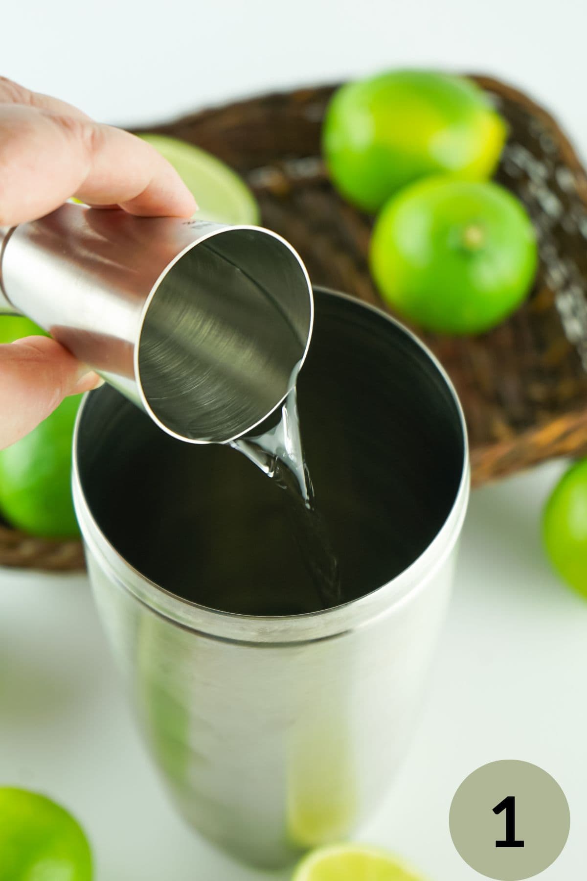 step 1 hand pouring chilled vodka in cocktail shaker