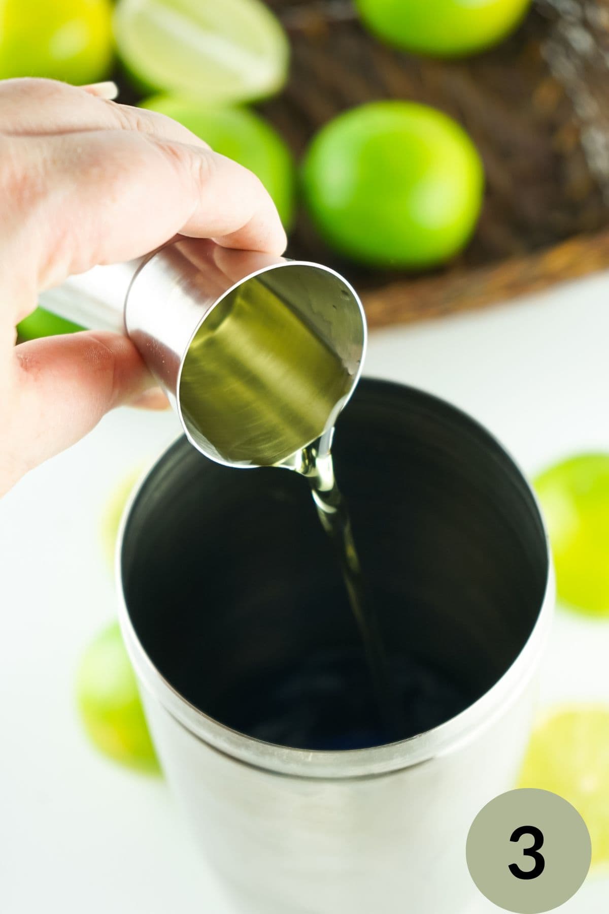 step 3 hand pouring lime juice in a cocktail shaker