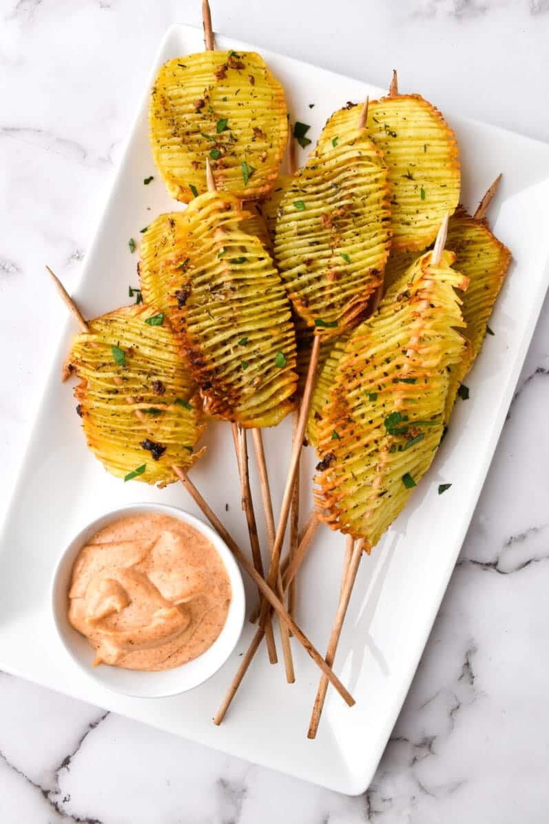 overhead view of potatoes on a skewer in a white serving tray