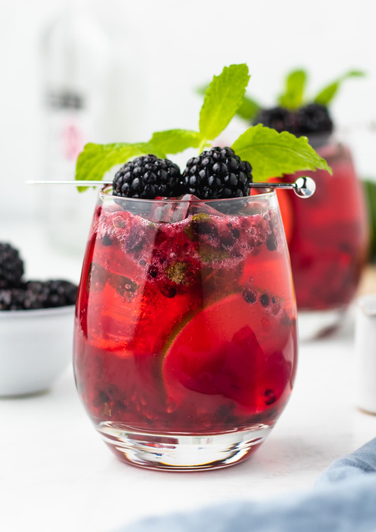 2 blackberry mojitos on a white table