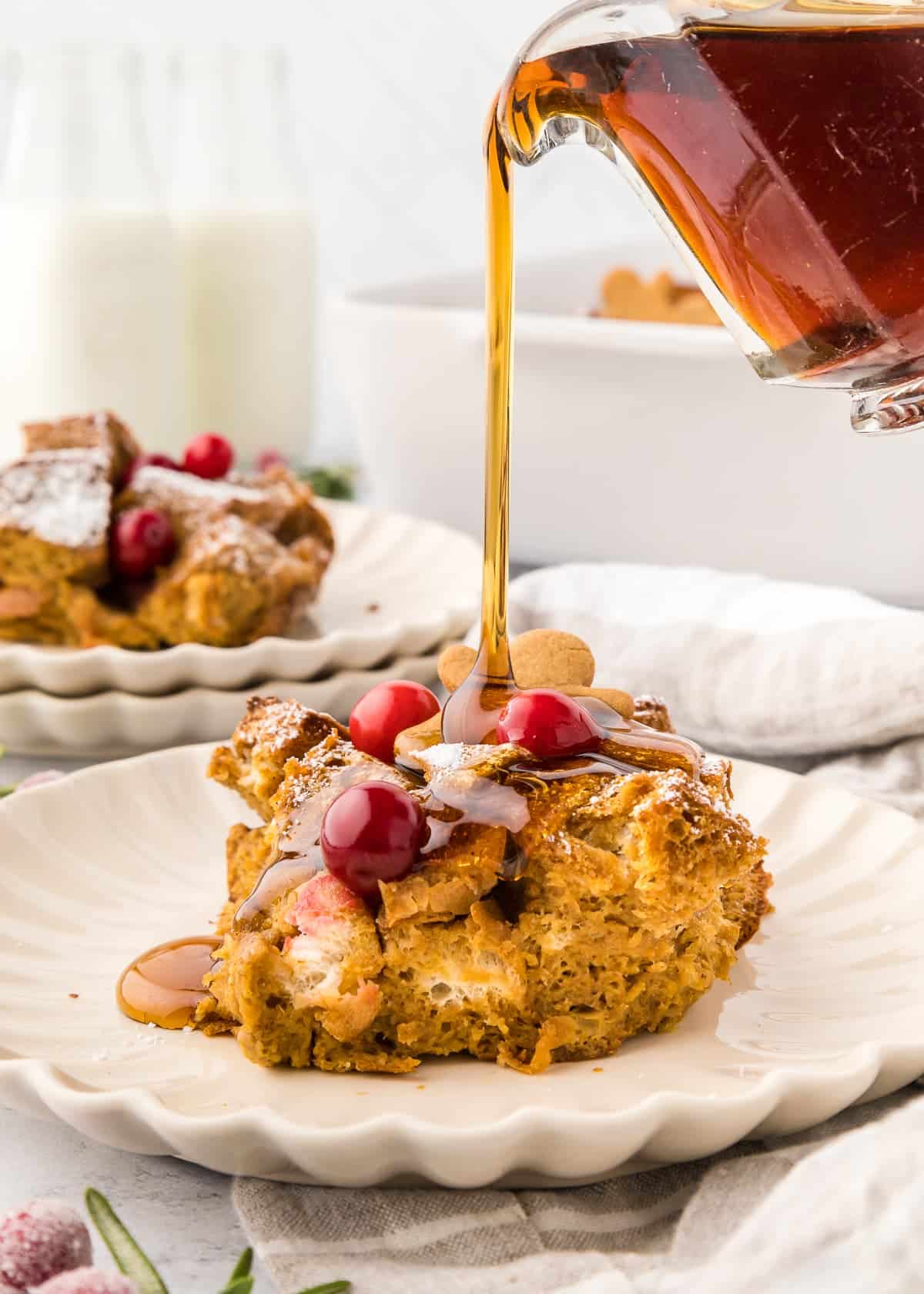 someone pouring syrup on a plate of French toast casserole