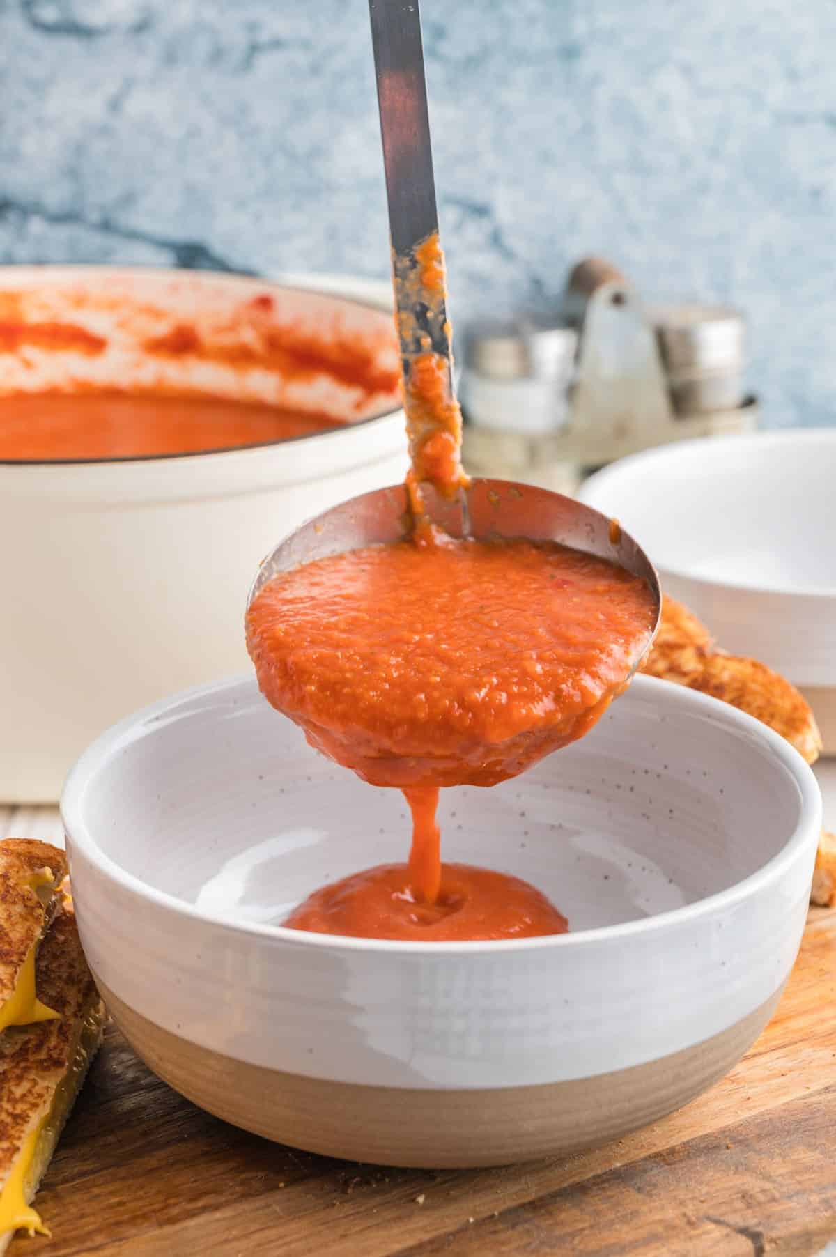 ladling vegan tomato soup into a bowl