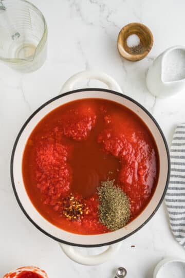 adding ingredients into dutch oven for vegan tomato soup