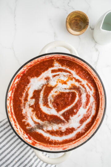 adding coconut milk, salt and pepper to tomato soup recipe