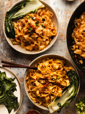 2 plates of garlic chili oil noodles on a marble table