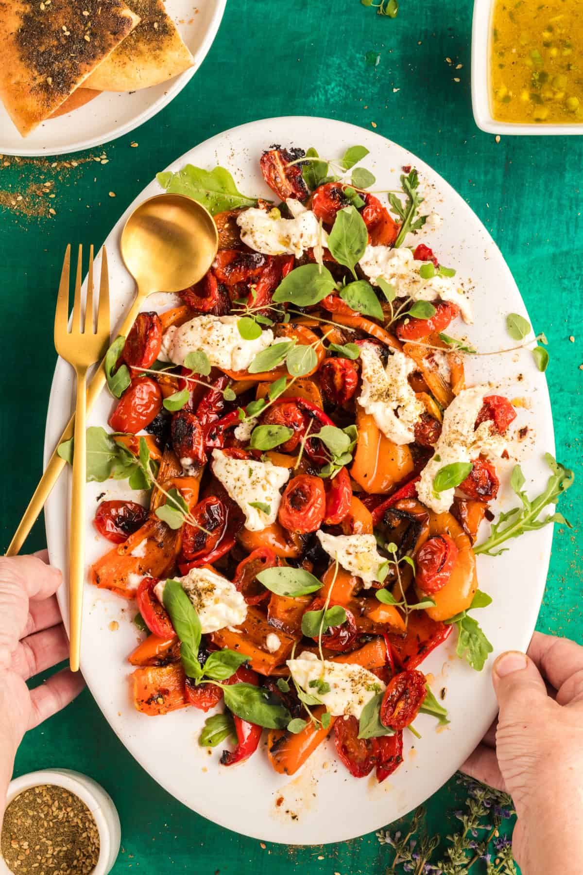 roasted bell pepper salad on a white plate topped with herbs