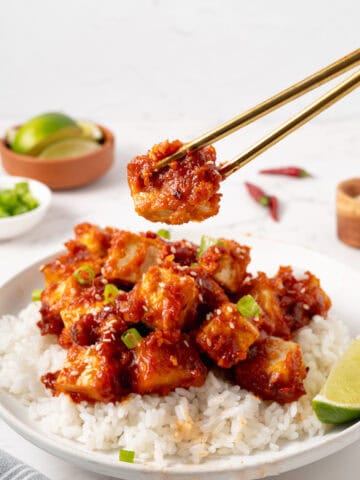 chopsticks holding up a piece of general tso's tofu